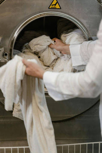 Person loading laundry into a washing machine